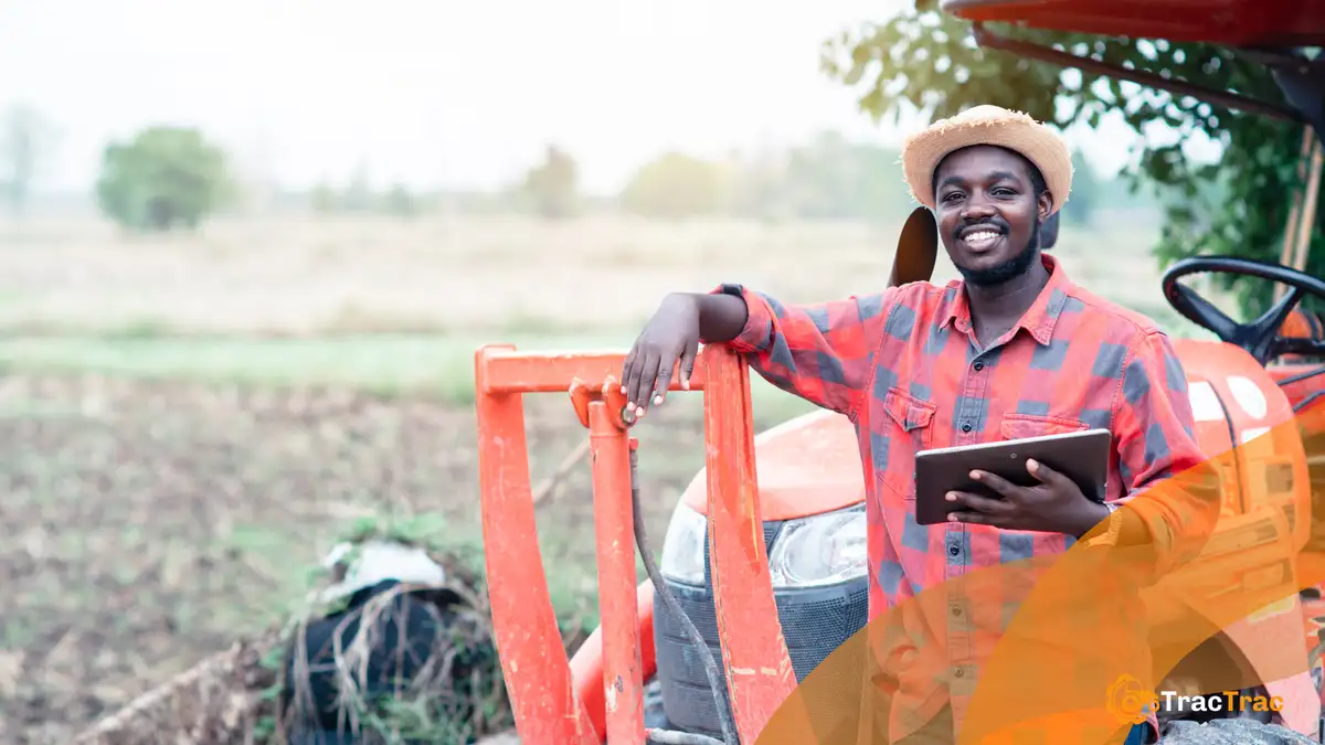man standing beside a tractor and holding a tablet